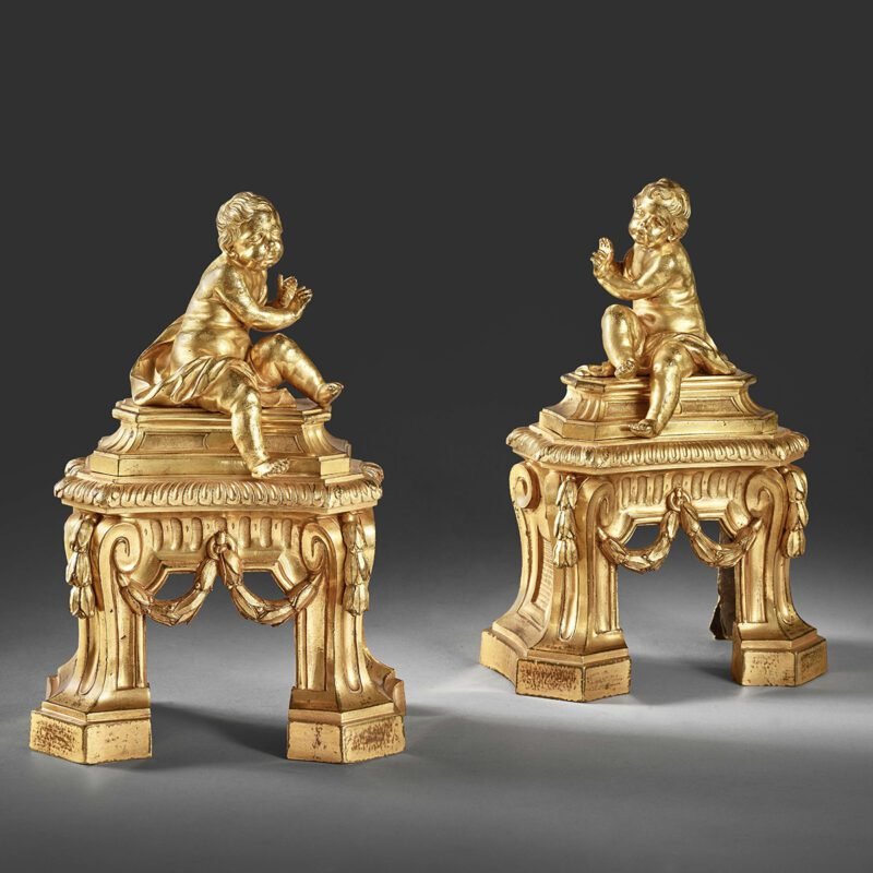 A pair of firedogs with seated putti