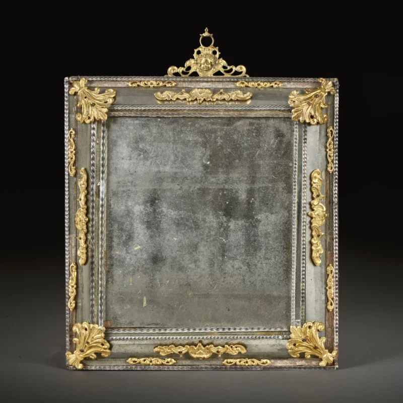 Miroir vénitien du XVIIe siècle avec cadre sculpté, décor de feuilles d’argent et éléments en bronze doré.